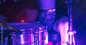 Beautiful female drummer praiseworthy playing drums in nightclub with big panoramic round window in twinkling concert RGB spot lights. Drummer girl concert concept.