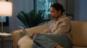 Upset stressful woman African American girl homeowner confused shocked lady fail online exam on laptop negative result bad news anxious female on sofa computer problem failure shock at evening home