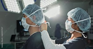 Surgery, hospital and doctors tie mask in operating room for medical service, preparation and operation. Healthcare team, safety scrubs and people with uniform for emergency, procedure and protection