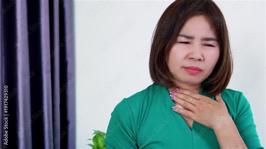 Sick Asian woman coughing and suffering from a sore throat Concept of seasonal flu, common cold, virus infection, and respiratory illness symptoms in adult female patient.