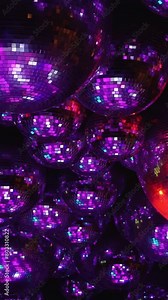 A close up of many red and silver disco balls. Scene is energetic and fun, as the balls are all lit up and appear to be dancing.