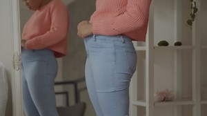 Weight gain woman buttoning pants with difficulties