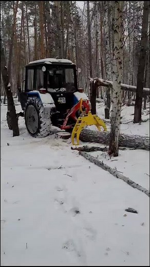 Blue Tractor Cutting Down Trees in Snowy Forest
