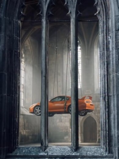 Hanging Supra in a gothic castle using Nana Banana Pro Kling 2.5 Turbo 🏰🚗 Photo prompt 1 (main hall): A raw, photorealistic documentary-style photograph inside an ancient, gloomy castle great hall. A vibrant orange Toyota Supra MK4 (A80) is suspended in the center of the vaulted space by thick industrial steel cables, heavy chains, and rigging harnesses attached to its chassis. Diffused cold natural light through tall, dirty gothic windows, deep shadows, damp stone floors, film grain, handheld