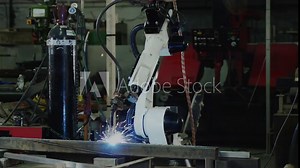 Robotic arms assembling and welding steel frames in a manufacturing plant, steel frame production, robotic welding process line to finishing product.