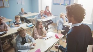 Enthusiastic Teacher Explains Lesson to a Classroom Full of Bright Diverse Children. In Elementary School with Group of Smart Multiethnic Kids Learning New Stuff.Teacher Over the Shoulder Camera