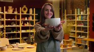 Female potter artist sculptor work with clay master class ceramic workshop Caucasian smiling woman girl creating pot handmade plate showing at camera small business owner crafting store manufacture