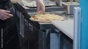 Chef making savoury italian pizza on the kitchen table. Chef making the pizza by spreading the cheese ingredients on dough. Chef making delicious pizza dish at the italian cuisine restaurant. Tomatoes