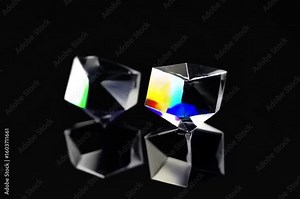 Two beautiful prisms that refract light, creating stunning spectrum of colors. The prisms have perfect geometric shape, and reflect beautifully against each other