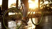 Close up footage of female feet cycling a bicycle in the morning park...