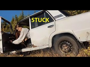 Girl with old car stuck in mud and forest