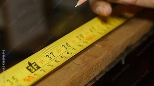 Carpenter using tape measure and pencil on wood slow motion
