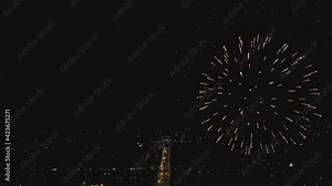 Colorful fireworks exploding in the sky above the city. Aerial view of the city at night, glowing with many lights. City road that goes into the distance.