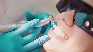 Dentist hygienist makes oral hygienic cleaning in dentistry for woman.