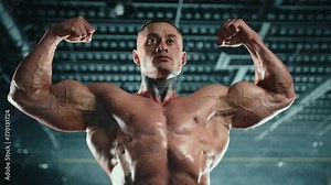 An impressively muscled bodybuilder flexes his biceps, showcasing the detailed definition and strength of his well-trained physique against the backdrop of the gym. Camera 8K RAW.