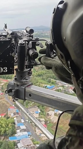 Military Helicopter Gunner in Action Over Cityscape