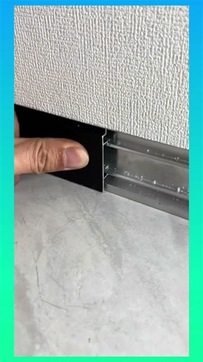 Installing a sleek black baseboard trim to create a clean, modern transition between wall and floor