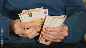 Man counting a stack of fifty euro banknotes, showcasing the details of cash handling and financial transactions