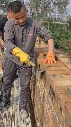 Pour cement and insert bricks until they form the length of the fence wall. #construction #shorts