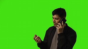 Young man talking on mobile phone standing against green screen studio background Free Stock Video Footage