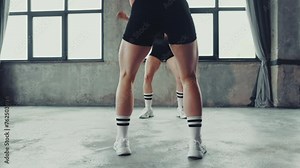 Focused athlete woman squatting with weights as her fit partner mirrors movement, in motion at gym. Concept of professional sport, active lifestyle, bodybuilding, energy, motivation. Ad