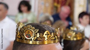 During a church wedding, wedding crowns are placed on the heads of the newlyweds.