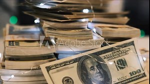 A lot of money 100 dollars money cash rotate, profit made on holidays in glowing lights. US hundred dollar bills bundles stack on blurred background. Exchange currency market.