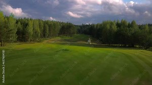 small helicopter flying over a golf course, helicopter on a golf course, civilian helicopter taking off from a golf course, small helicopter landing on a golf course