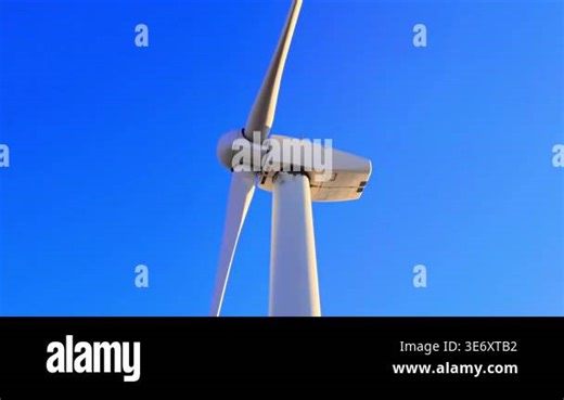 White wind turbine nacelle and rotating three blades against a solid blue sky background in daylight. Close up of wind turbine. Aerial view Stock Video Footage - Alamy