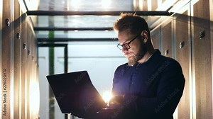 Male computer technician is navigating a laptop in a server unit