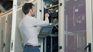 Server IT Engineer In Data Center Server Room.Network Engineer Working Laptop Computer.Server Rack Room Works.Programmer Checks A work Of Server At A Data Center.