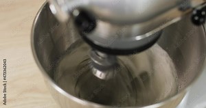Baker is mixing ingredients in bowl cooking dough baking cake using electric mixer, closeup view. Steps of cooking baking and confectionery. Preparing sweet food dessert in kitchen at home.