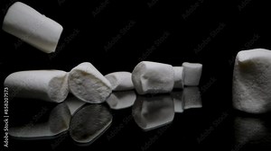 White Marshmallows Falling onto a Black Reflective Table, Slow Motion, Close-Up.
