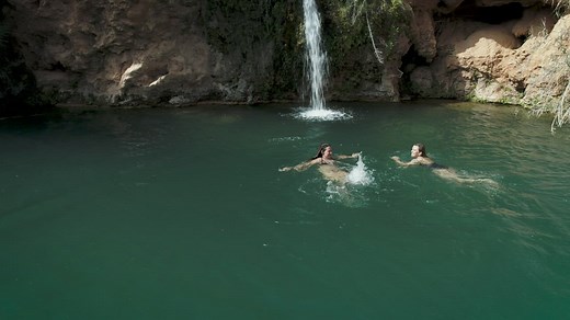 Two girls swimming in a pond with a waterfall - Free Stock Video