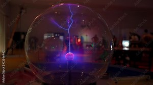 An electric plasma ball generates luminous flames in a captivating close-up shot. The sphere exhibits blue-violet electric lightning in a laboratory setting.