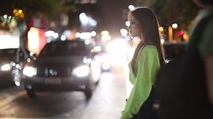 Young millennial woman crossing street walking at night in urban city