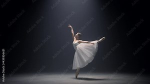 Sensual ballerina jumping on stage. Ballet dancer dancing pointe shoes indoors.