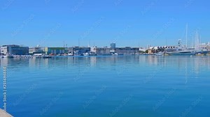Old gray rusty bollard on a pier against the blue sea with ships moored at the pier of the seaport of Valencia. Shot in motion