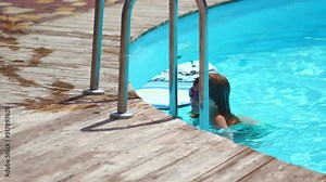 a little girl swims and dives in the pool wearing swimming goggles.