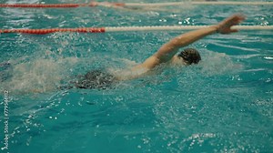 Athletic man swim freestyle in swimming pool. Professional male swimmer training in swimming pool. Active lifestyle and sport concept