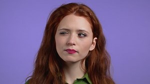 clip-1071244252-portrait-hesitant-woman-on-purple-background-young