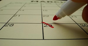 A hand writing on a calendar