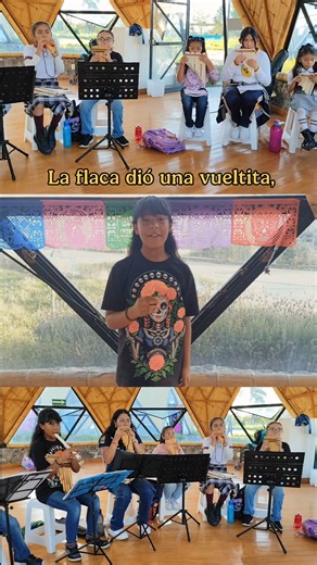 En la Feria de las Calacas, la flaca puso en el Cenart a su esqueleto a bailar, oyó a niñas y niños decir Zango-Zango sabaré y se puso a zapatear. 💃 Con guitarras 🎸 y tambores 🪘la calaca sonreía, ¡Ay, qué ritmo tan bonito, me recuerda a mi vida! ❤️ Edgar dirigió con gran emoción, y David en percusiones que, ¡puso ritmo al corazón! 💕 Jaime sopló las quenas 🪈, sonando con ritmo y alegría, la flaca dio una vueltita, ¡y bailó todo el día! “La Llorona” la espantó, pero luego se calmó, con “El có