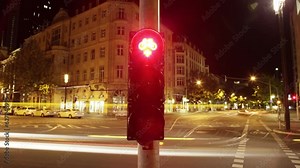 Through the pedestrian's perspective, this timelapse captures a city street at night, marked by colorful traffic light, lined buildings, trees, streetlights, and blurred vehicles due to long exposure