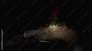 Slow Aerial Drone View of City Street with Skyscraper Rooftops and Road traffic, Birds Eye Overhead Top Down View at Dusk or Night with flashing City lights