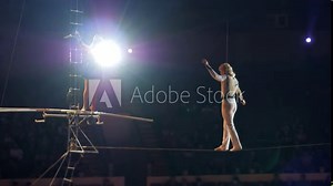 Performance of three aerial tightrope walkers gymnasts in white suits in the circus. Aerialists arrange a show for the audience under the dome of the circus, a tightrope walker walks on a rope.