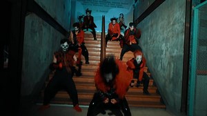Group of people in red and black costumes with masks dancing in a stairwell.
