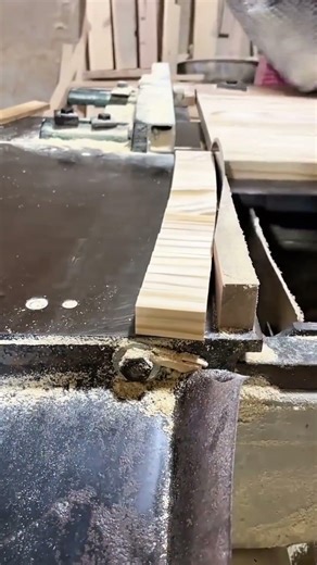 Slicing a wooden plank into thin strips using a table saw machine in a carpentry workshop