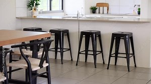 Stone bench top kitchen with bar stools with adjacent dinging table. Modern all white kitchen with tile splashbacks