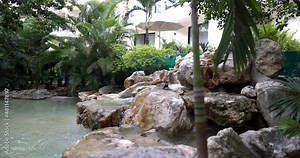 Beautiful rocky cascade and pond behind log railing